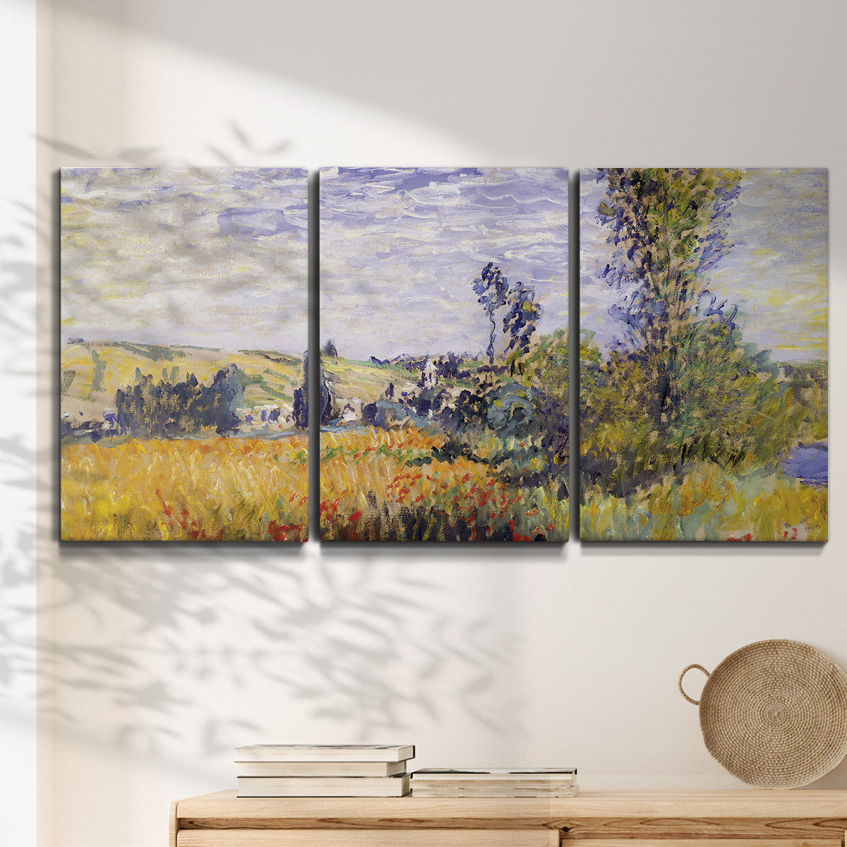 Three-panel canvas wall art featuring river village landscape with hills, displayed in a minimalist living room above a console table.