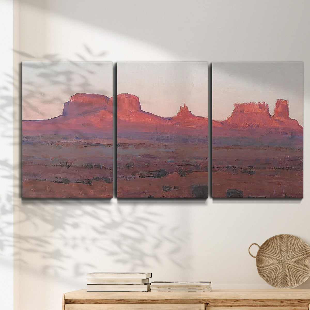 Three-panel canvas wall art featuring red rock desert formations at dusk, displayed in a minimalist living room above a console table.