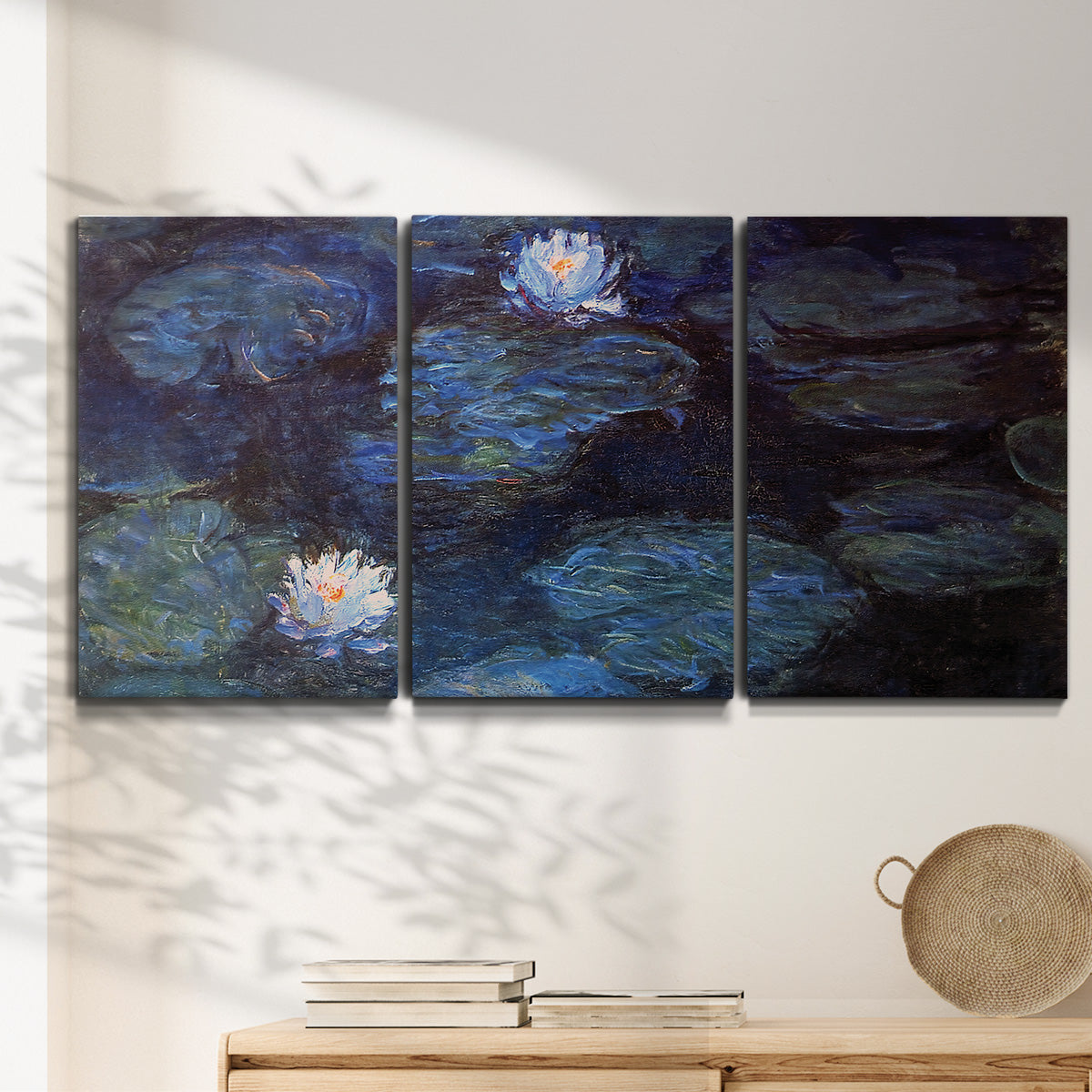 Three-panel canvas wall art featuring deep blue water lily reflections, displayed in a minimalist living room above a console table.