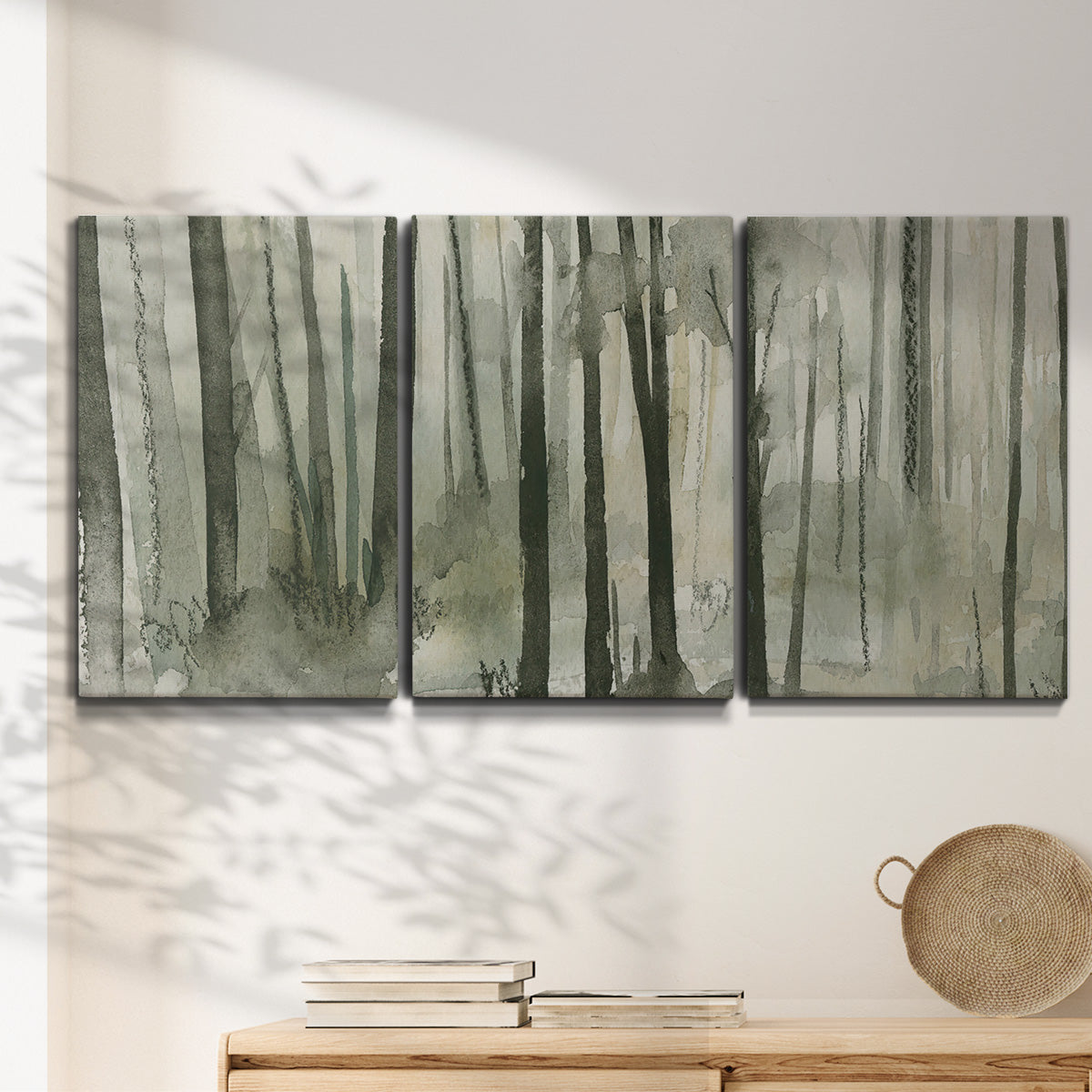 Three-panel canvas wall art featuring wooded forest path watercolor, displayed in a minimalist living room above a console table.