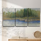 Three-panel canvas wall art featuring riverbank landscape with trees, displayed in a minimalist living room above a console table.