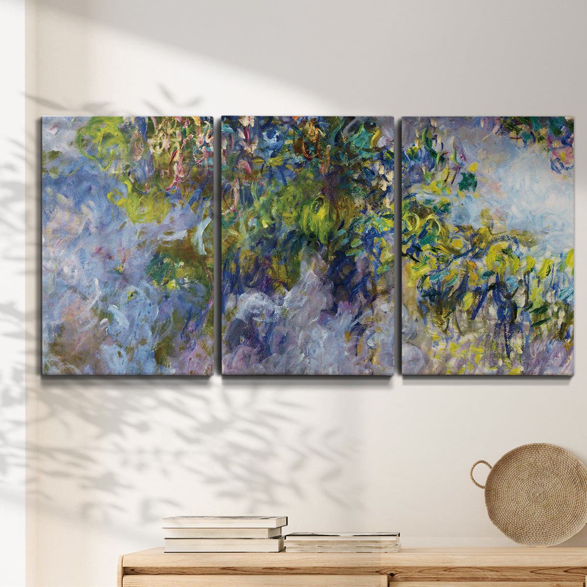 Three-panel canvas wall art featuring cascading purple wisteria blooms, displayed in a minimalist living room above a console table.