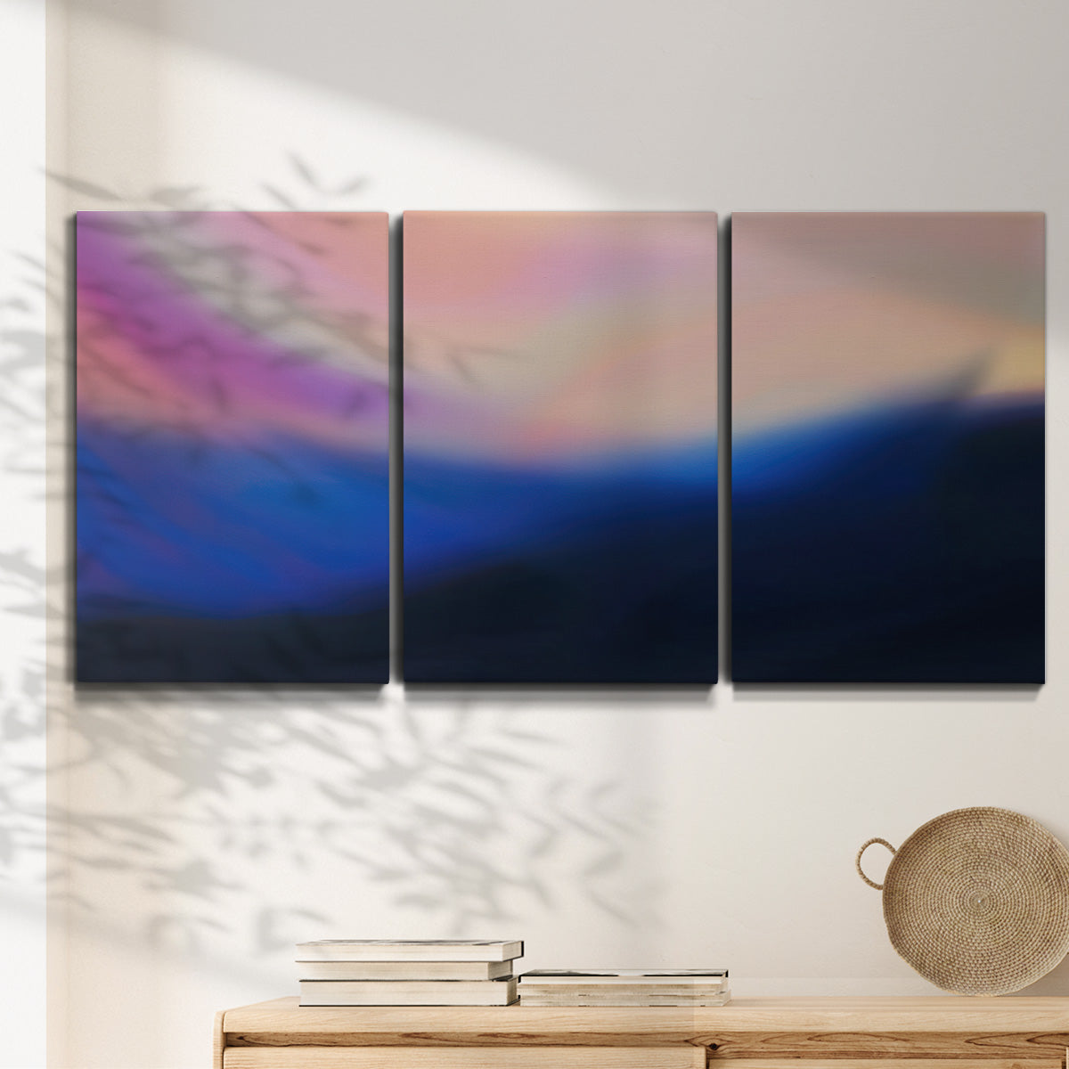 Three-panel canvas wall art featuring smooth abstract sunset color gradient, displayed in a minimalist living room above a console table.