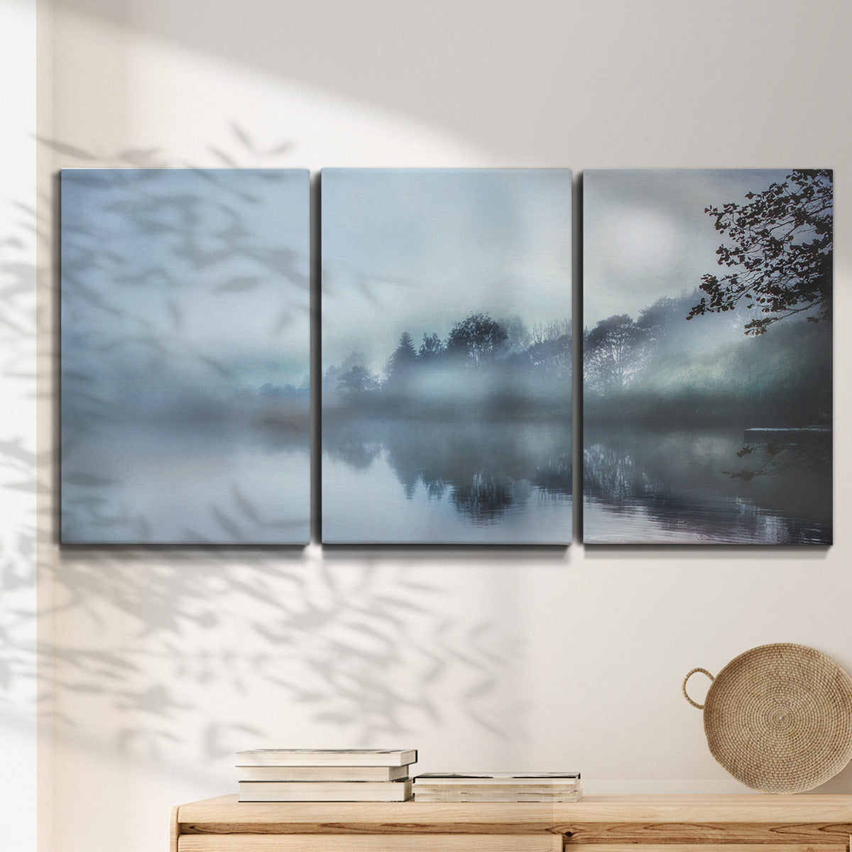 Three-panel canvas wall art featuring calm waters at sunrise photograph, displayed in a minimalist living room above a console table.