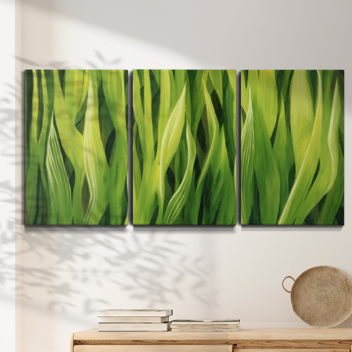 Three-panel canvas wall art featuring close view of tall green grass blades, displayed in a minimalist living room above a console table.