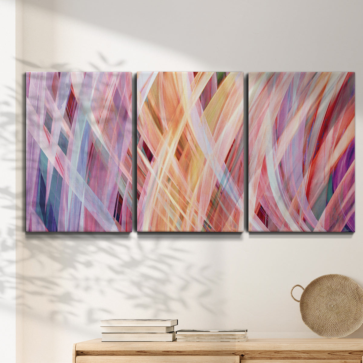 Three-panel canvas wall art featuring layered modern abstract color ribbons, displayed in a minimalist living room above a console table.