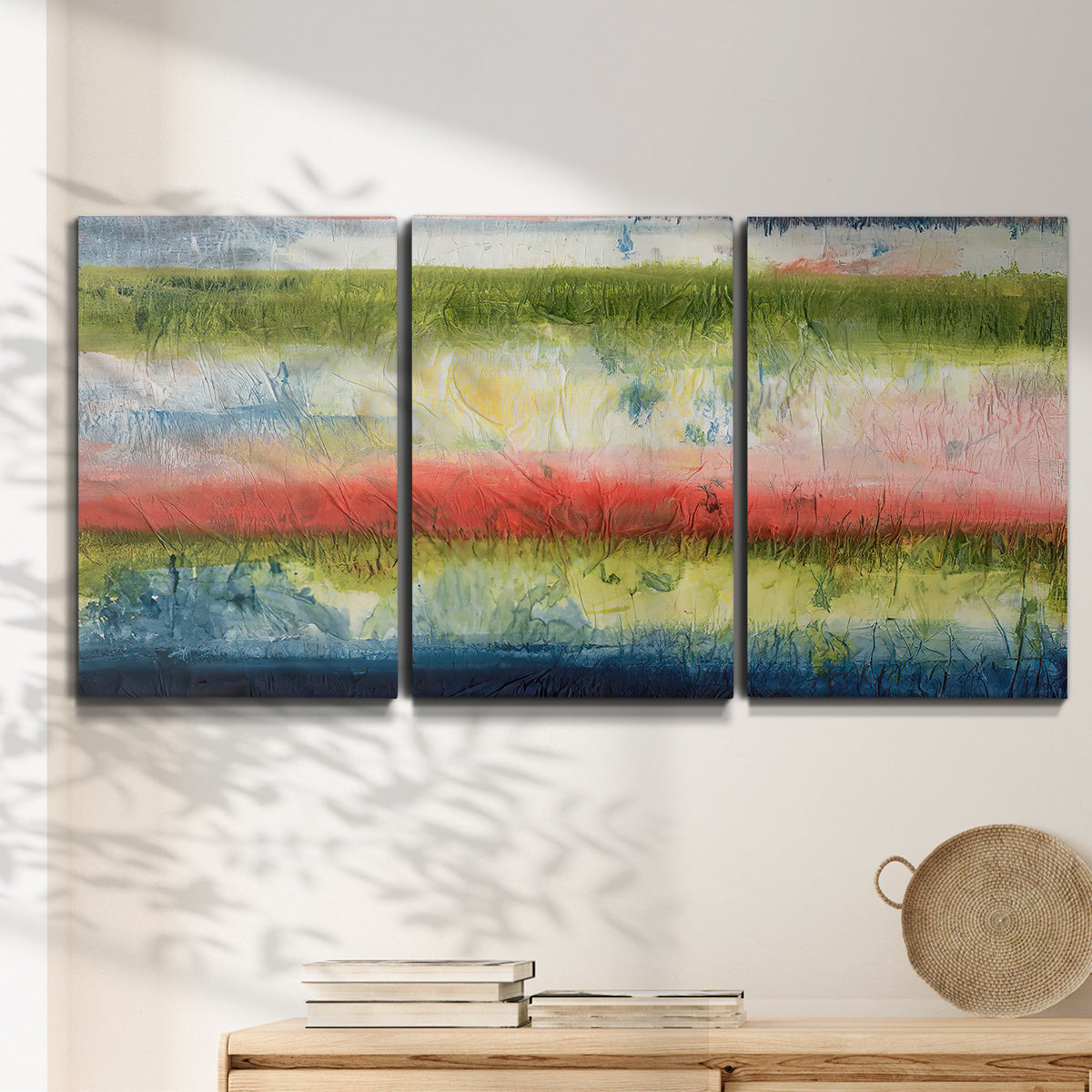 Three-panel canvas wall art featuring layered abstract color banding, displayed in a minimalist living room above a console table.