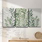 Three-panel canvas wall art featuring foraged leafy greens botanical study, displayed in a minimalist living room above a console table.