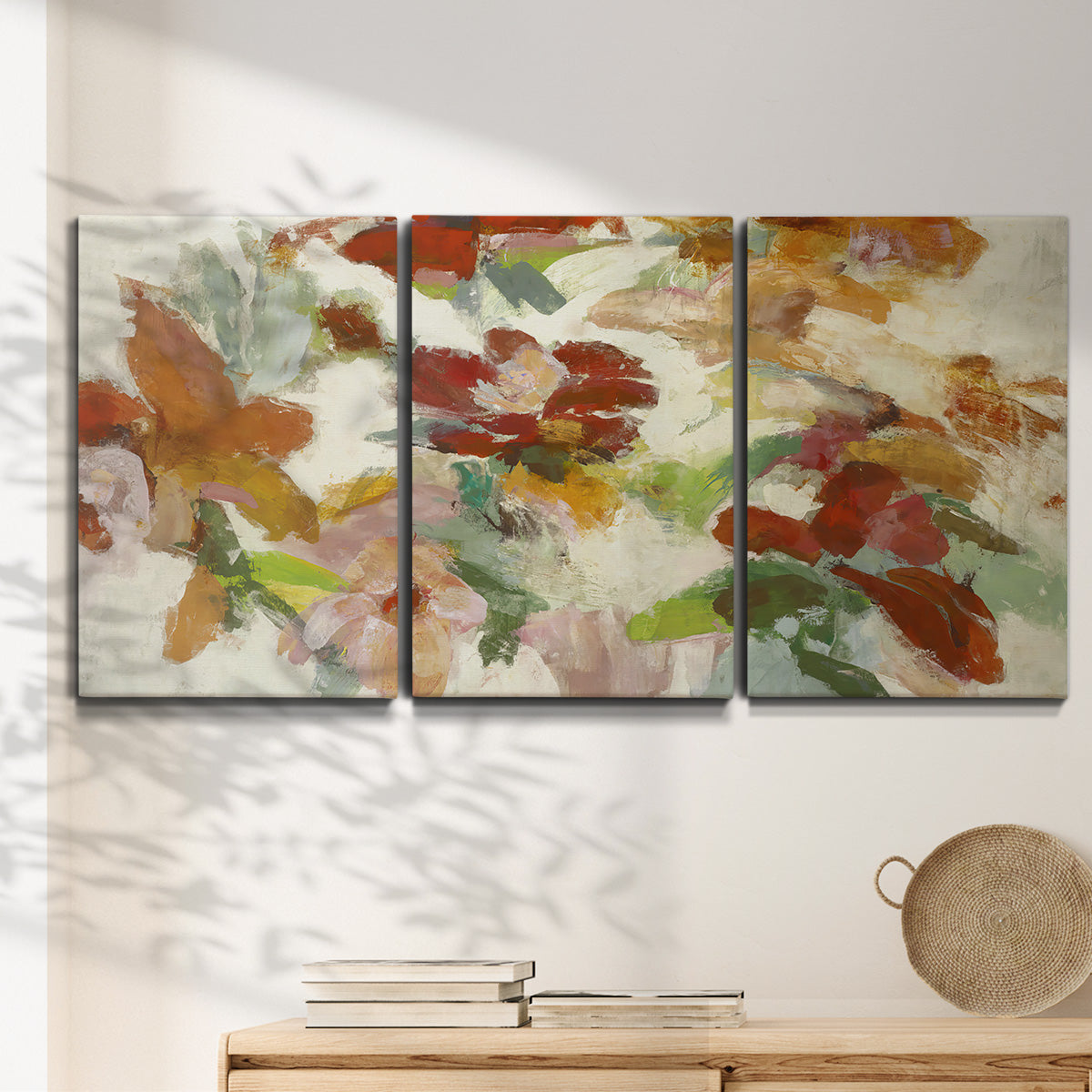 Three-panel canvas wall art featuring layered floral botanical impressions, displayed in a minimalist living room above a console table.