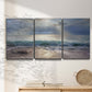 Three-panel canvas wall art featuring soft sunrise over open water, displayed in a minimalist living room above a console table.