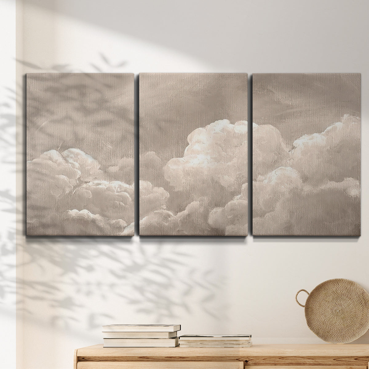 Three-panel canvas wall art featuring soft whimsical cloudscape, displayed in a minimalist living room above a console table.