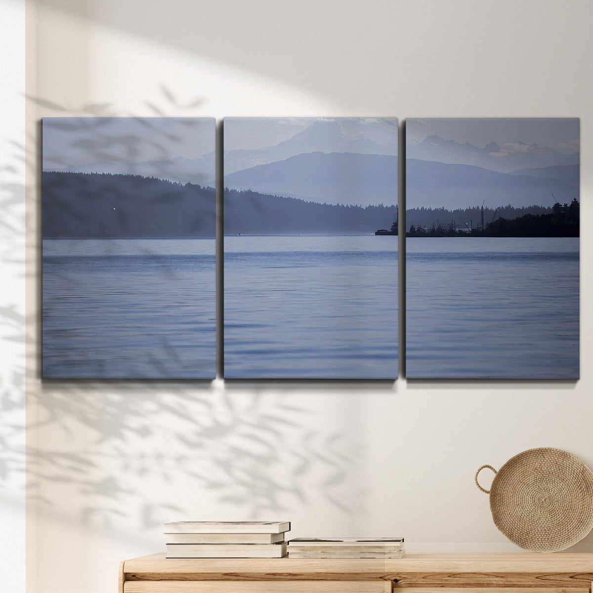 Three-panel canvas wall art featuring calm blue water landscape, displayed in a minimalist living room above a console table.