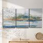 Three-panel canvas wall art featuring flowing blue abstract watercolor, displayed in a minimalist living room above a console table.