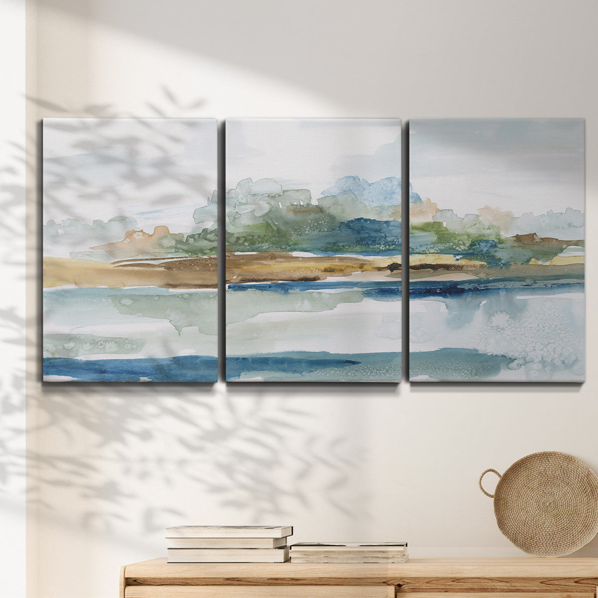 Three-panel canvas wall art featuring flowing blue abstract watercolor, displayed in a minimalist living room above a console table.