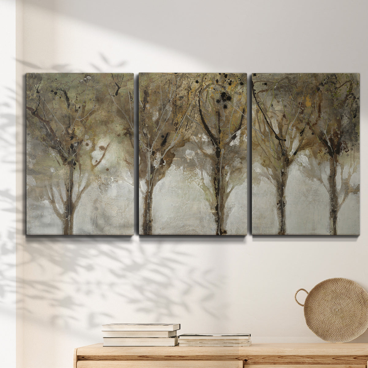 Three-panel canvas wall art featuring sunlight filtering through trees, displayed in a minimalist living room above a console table.
