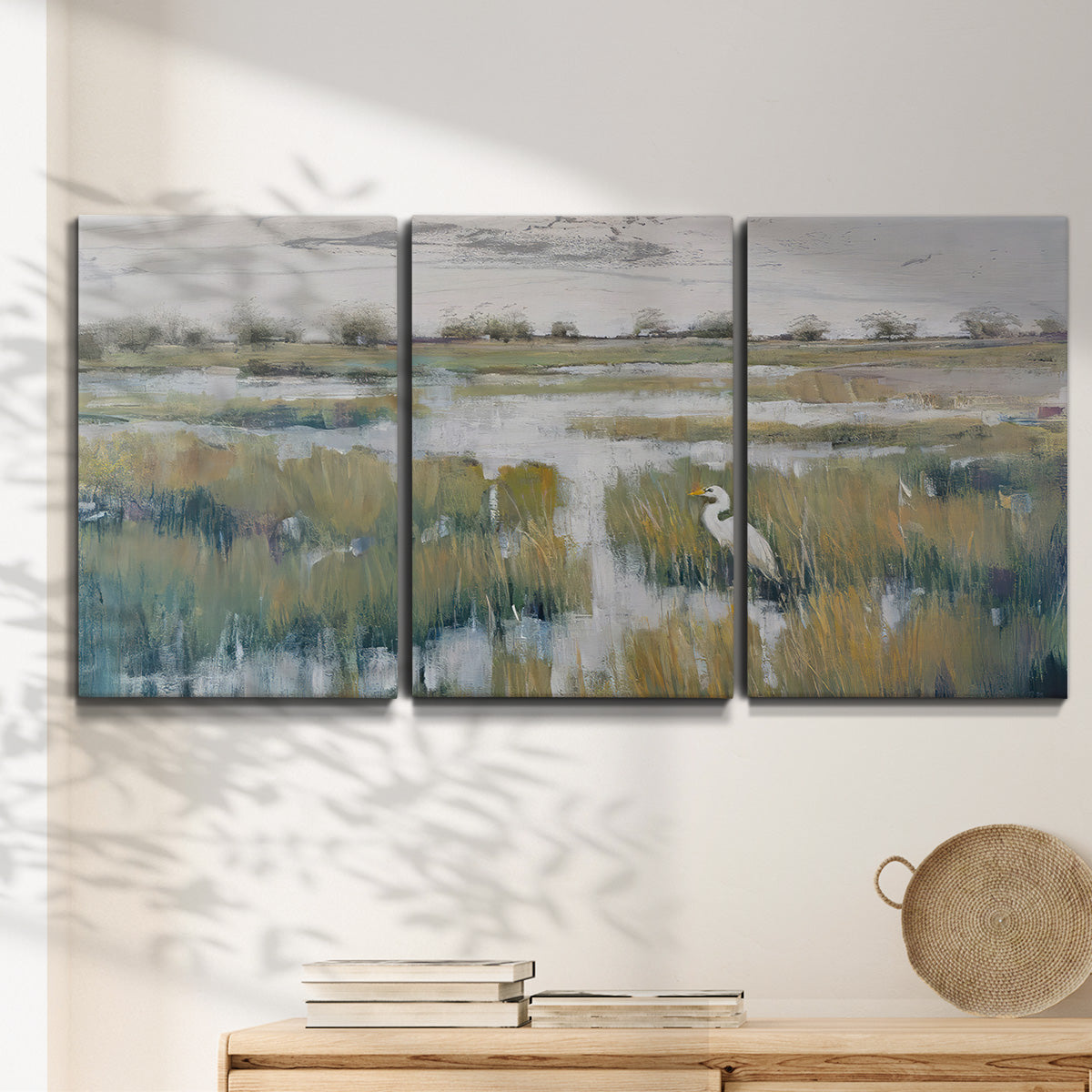 Three-panel canvas wall art featuring pastoral marshland landscape, displayed in a minimalist living room above a console table.