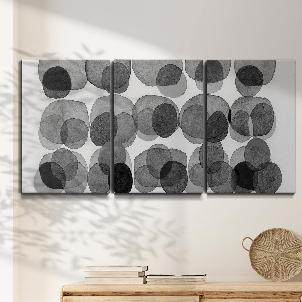 Three-panel canvas wall art featuring geometric abstract watercolor forms, displayed in a minimalist living room above a console table.