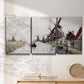 Three-panel canvas wall art featuring windmills beside calm water, displayed in a minimalist living room above a console table.