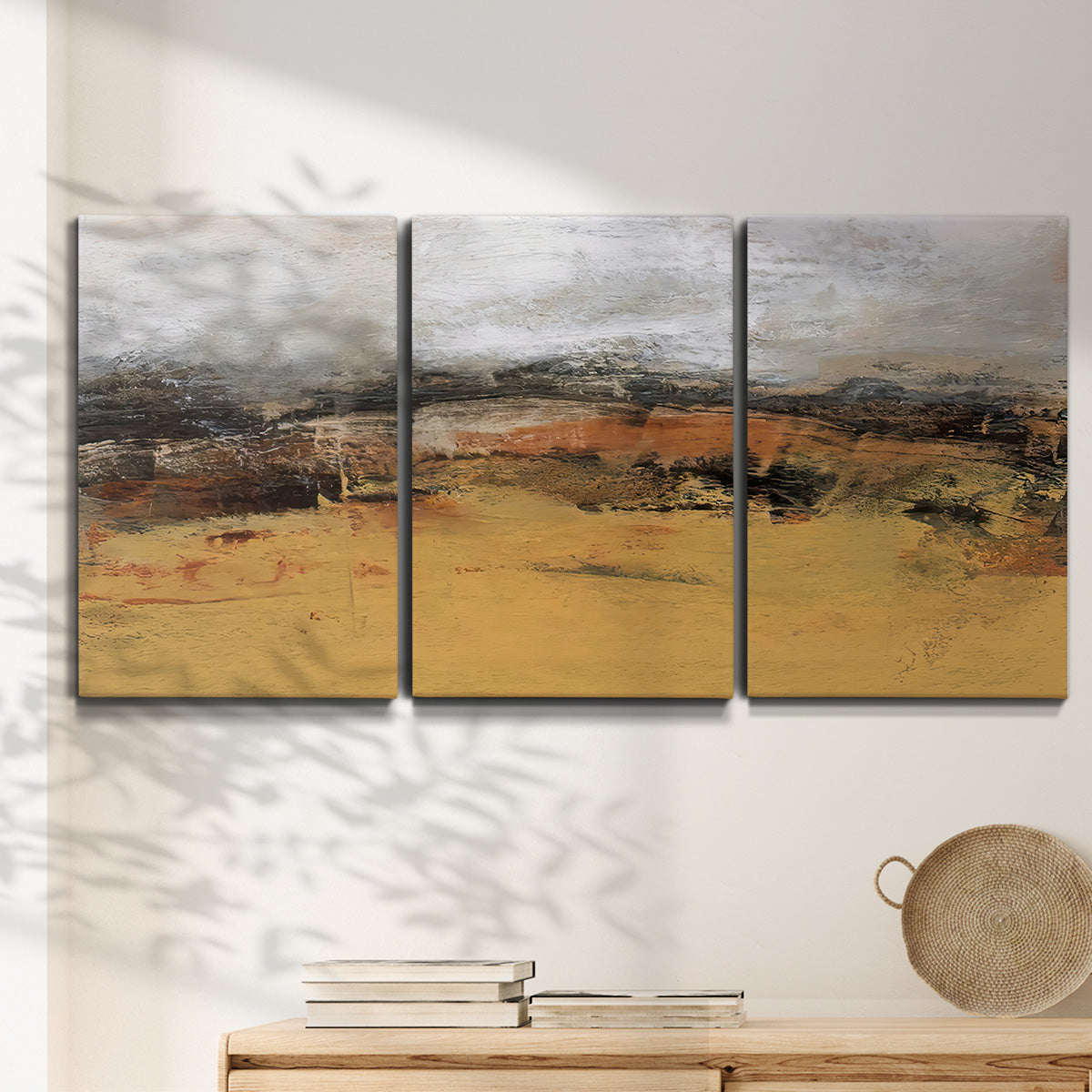 Three-panel canvas wall art featuring abstract bridge landscape in ochre, displayed in a minimalist living room above a console table.