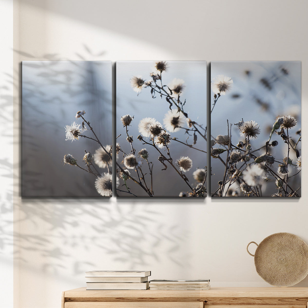 Three-panel canvas wall art featuring delicate spring blossoms on branches, displayed in a minimalist living room above a console table.