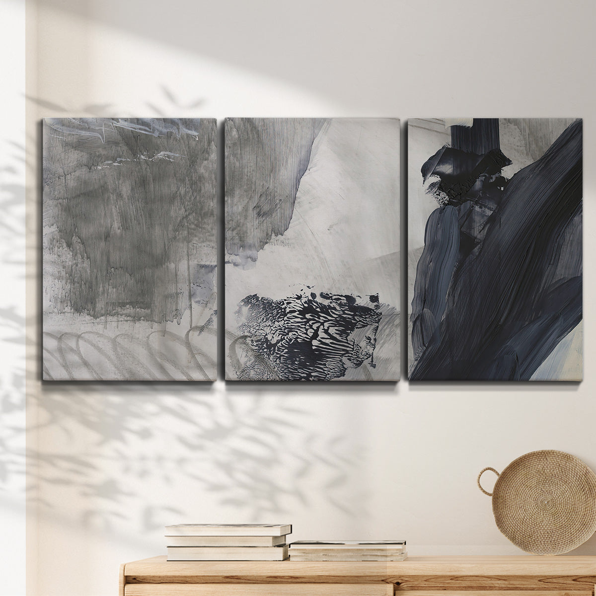 Three-panel canvas wall art featuring dark abstract atmospheric landscape, displayed in a minimalist living room above a console table.