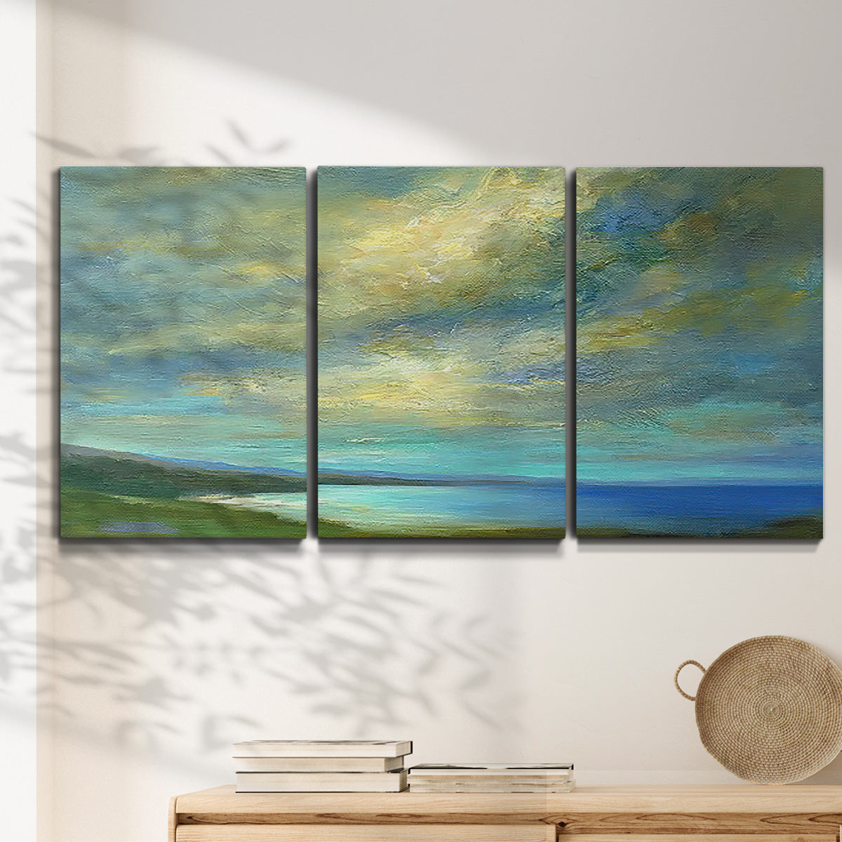 Three-panel canvas wall art featuring coastal shoreline with soft waves, displayed in a minimalist living room above a console table.