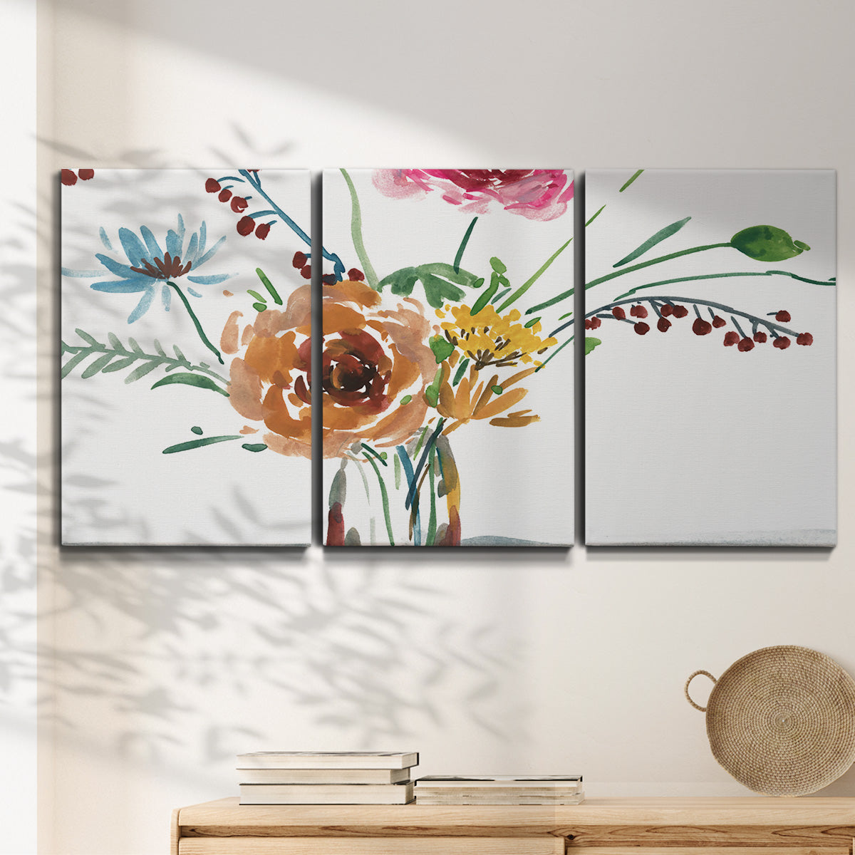 Three-panel canvas wall art featuring vibrant floral bouquet, displayed in a minimalist living room above a console table.