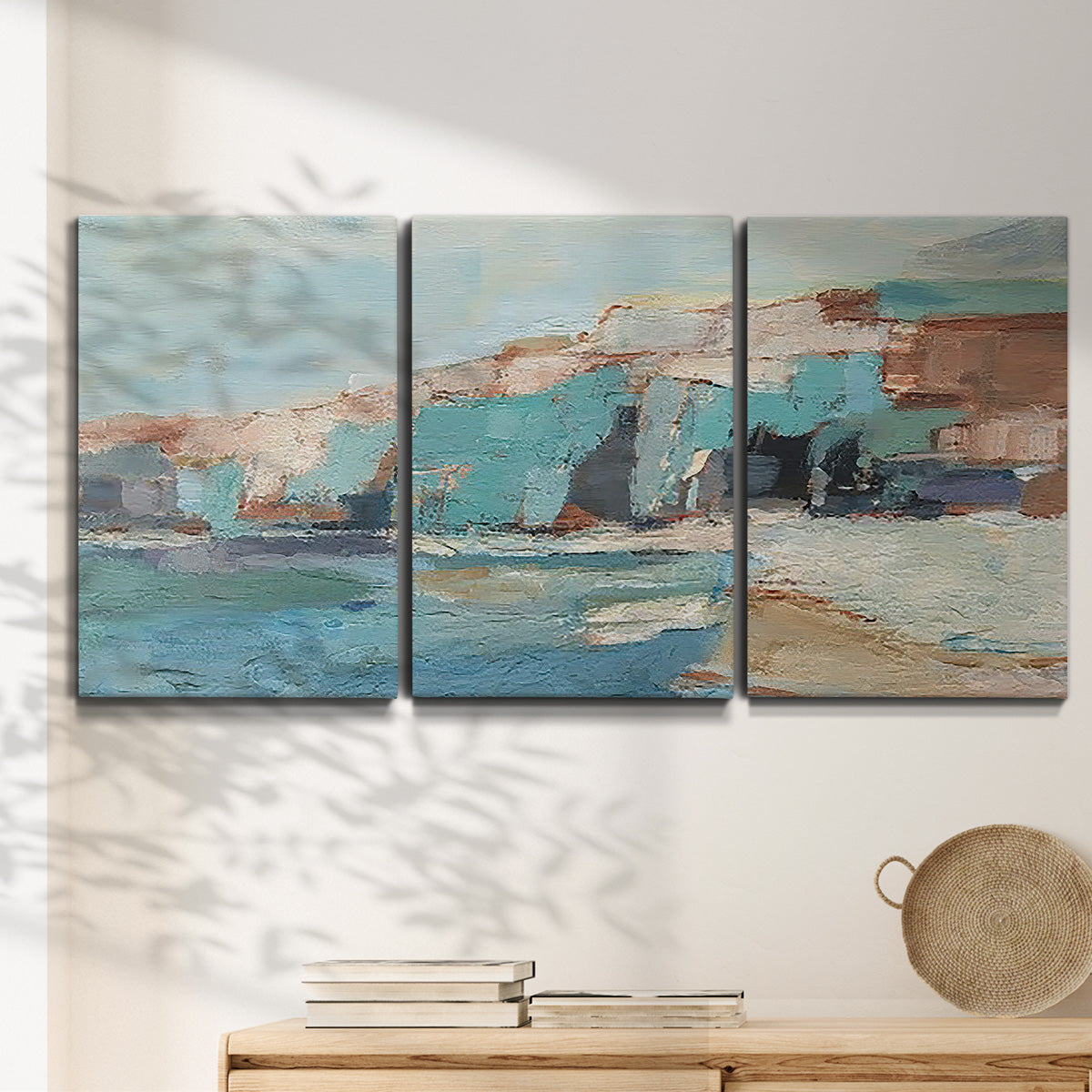 Three-panel canvas wall art featuring coastal shoreline with soft waves, displayed in a minimalist living room above a console table.