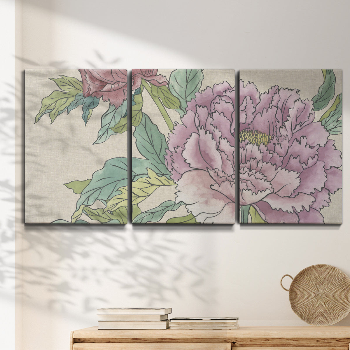 Three-panel canvas wall art featuring soft pink peony blossoms, displayed in a minimalist living room above a console table.