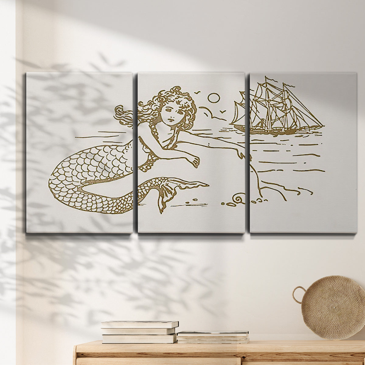 Three-panel canvas wall art featuring whimsical mermaid resting by sea, displayed in a minimalist living room above a console table.