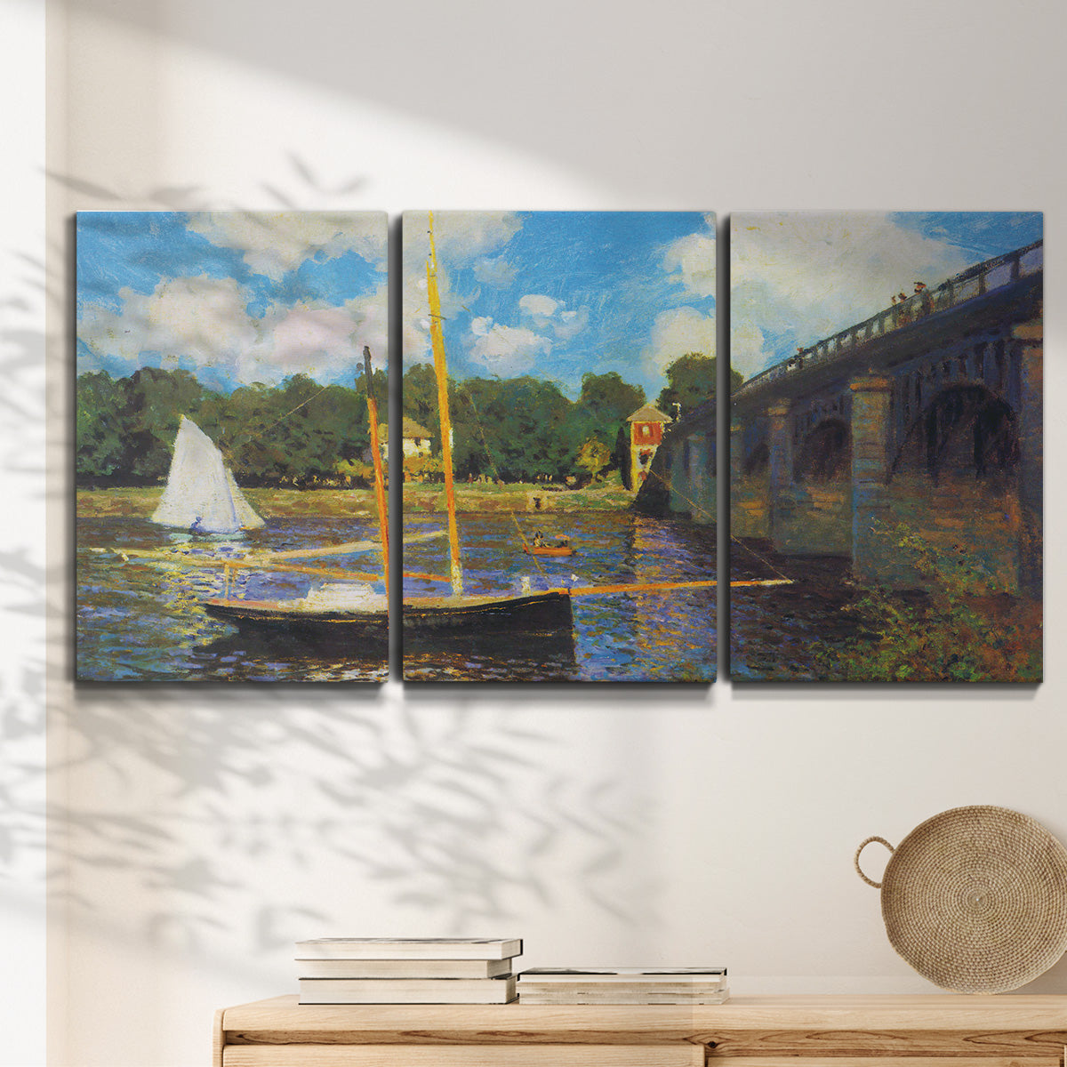 Three-panel canvas wall art featuring bridge crossing river landscape, displayed in a minimalist living room above a console table.