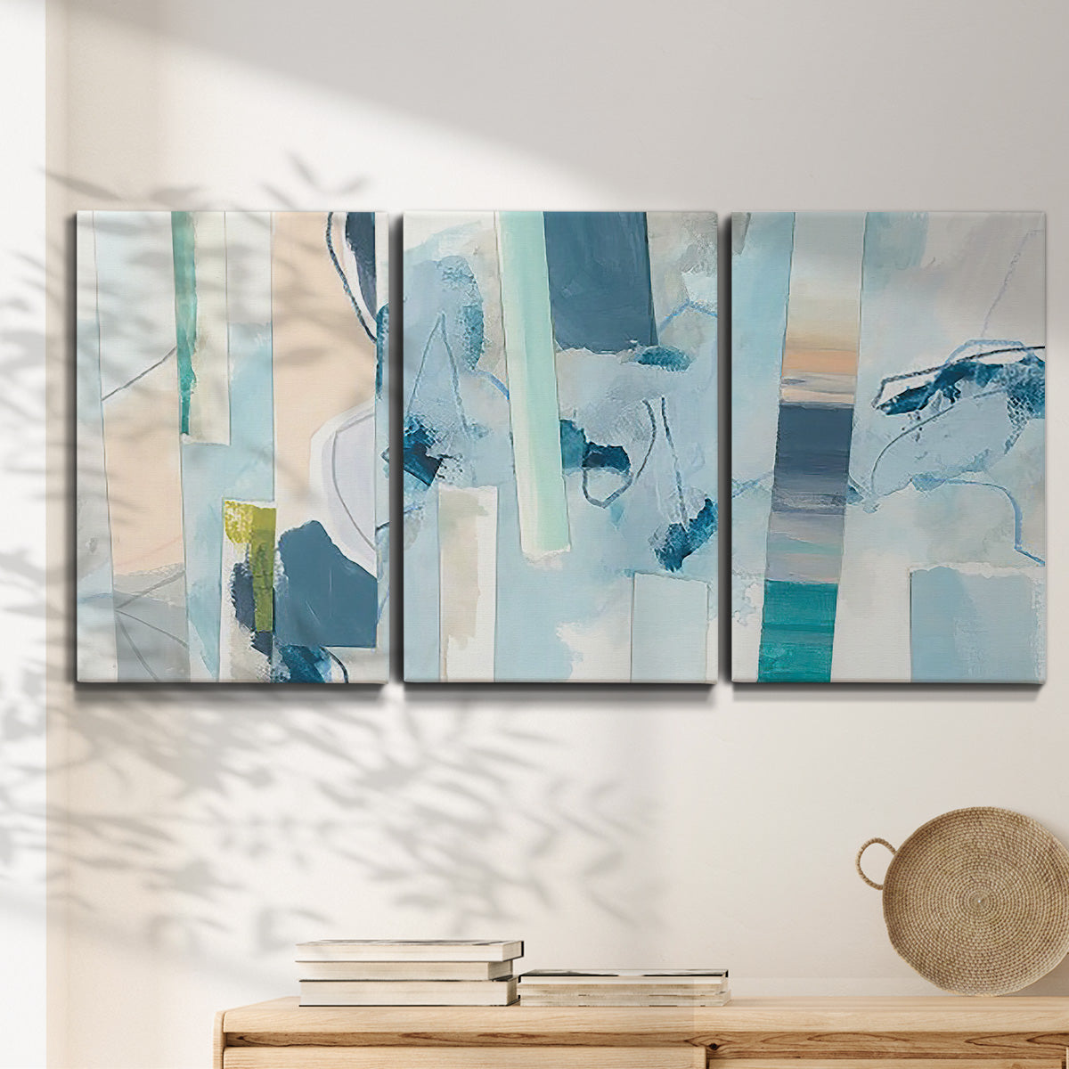 Three-panel canvas wall art featuring layered geometric abstract strata forms, displayed in a minimalist living room above a console table.
