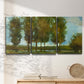 Three-panel canvas wall art featuring tall trees lining open landscape, displayed in a minimalist living room above a console table.
