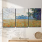 Three-panel canvas wall art featuring oat field with scattered poppies, displayed in a minimalist living room above a console table.