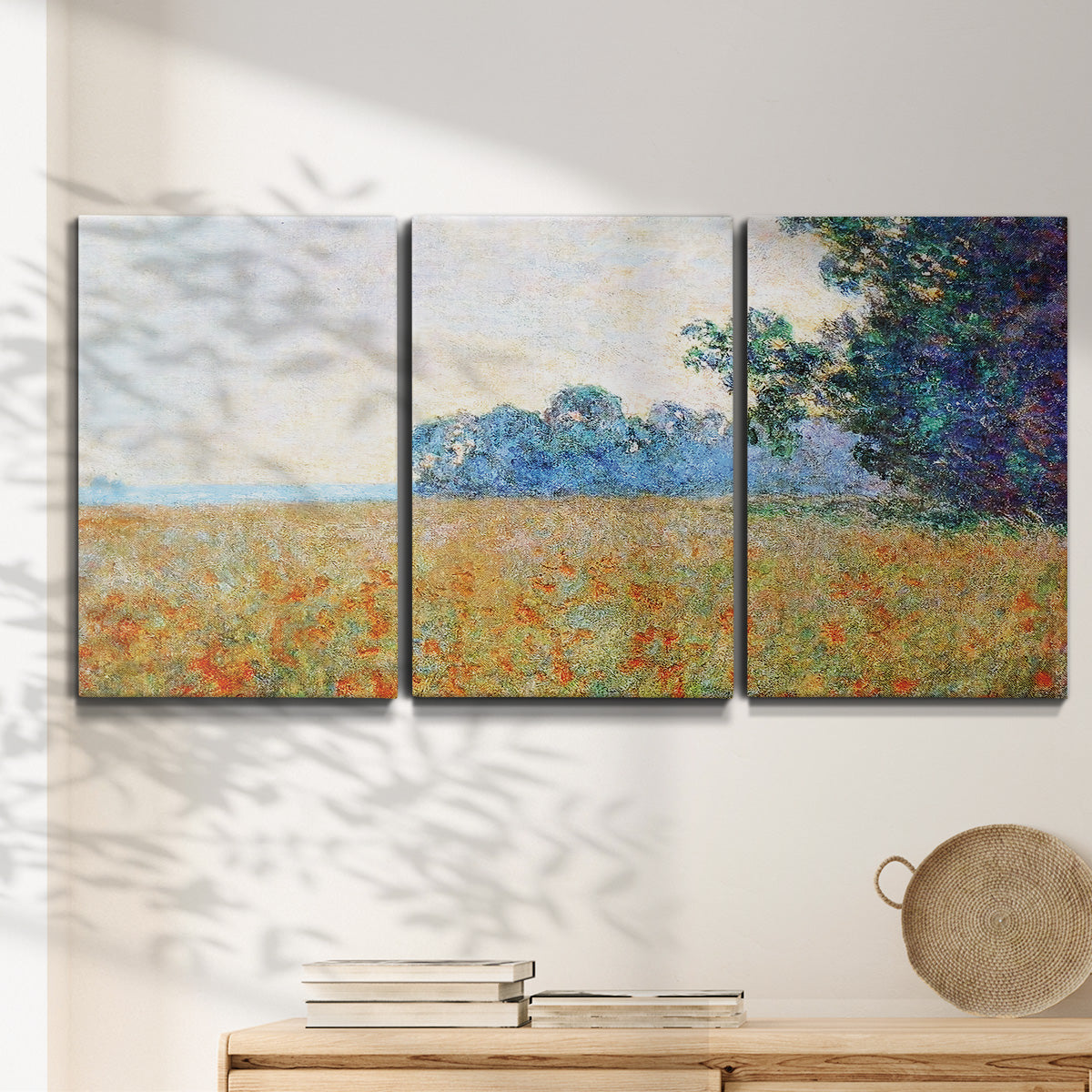 Three-panel canvas wall art featuring oat field with scattered poppies, displayed in a minimalist living room above a console table.