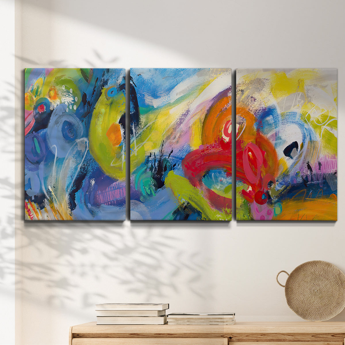 Three-panel canvas wall art featuring colorful abstract racing forms, displayed in a minimalist living room above a console table.