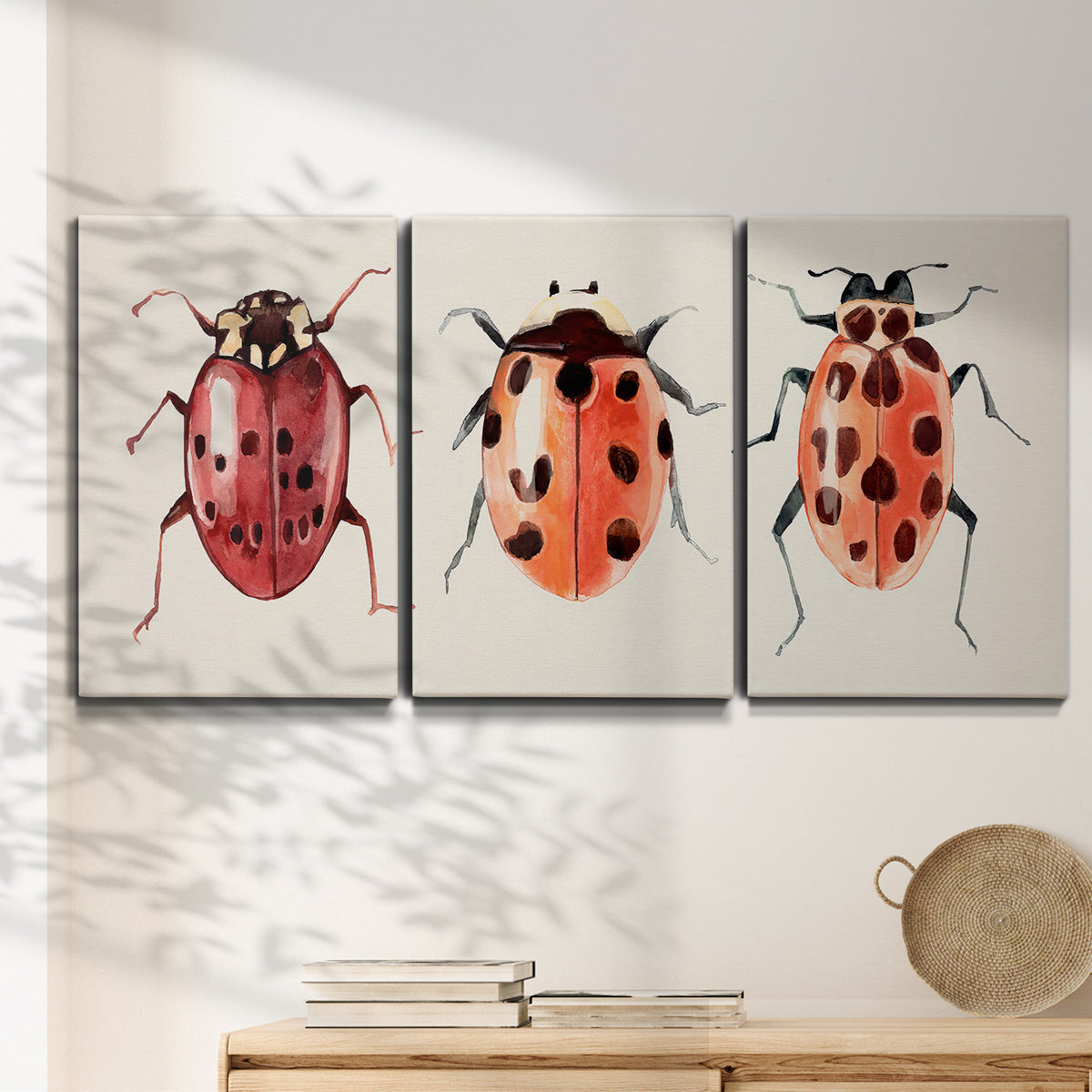 Three-panel canvas wall art featuring ladybugs on green foliage, displayed in a minimalist living room above a console table.