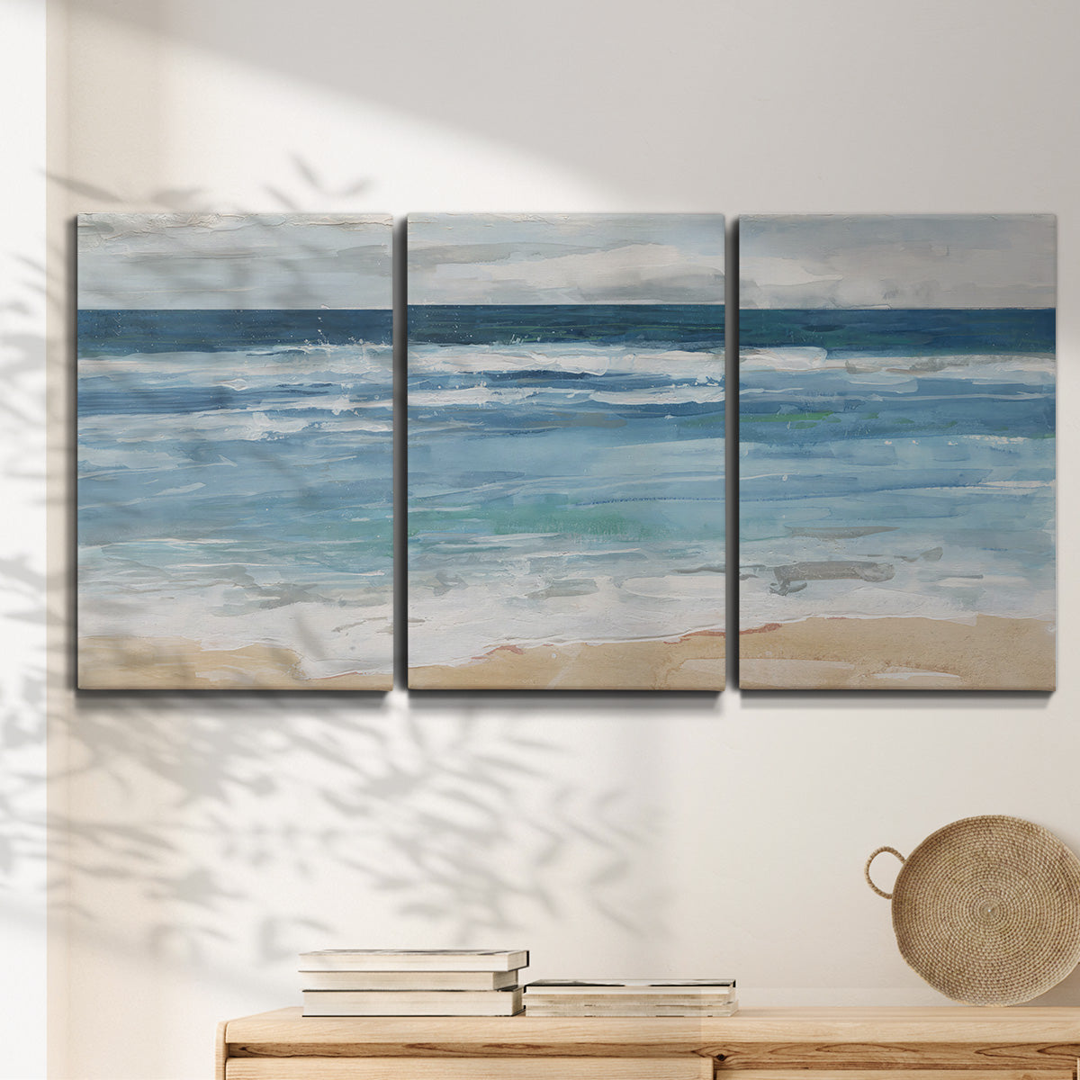 Three-panel canvas wall art featuring rolling ocean waves near shore, displayed in a minimalist living room above a console table.