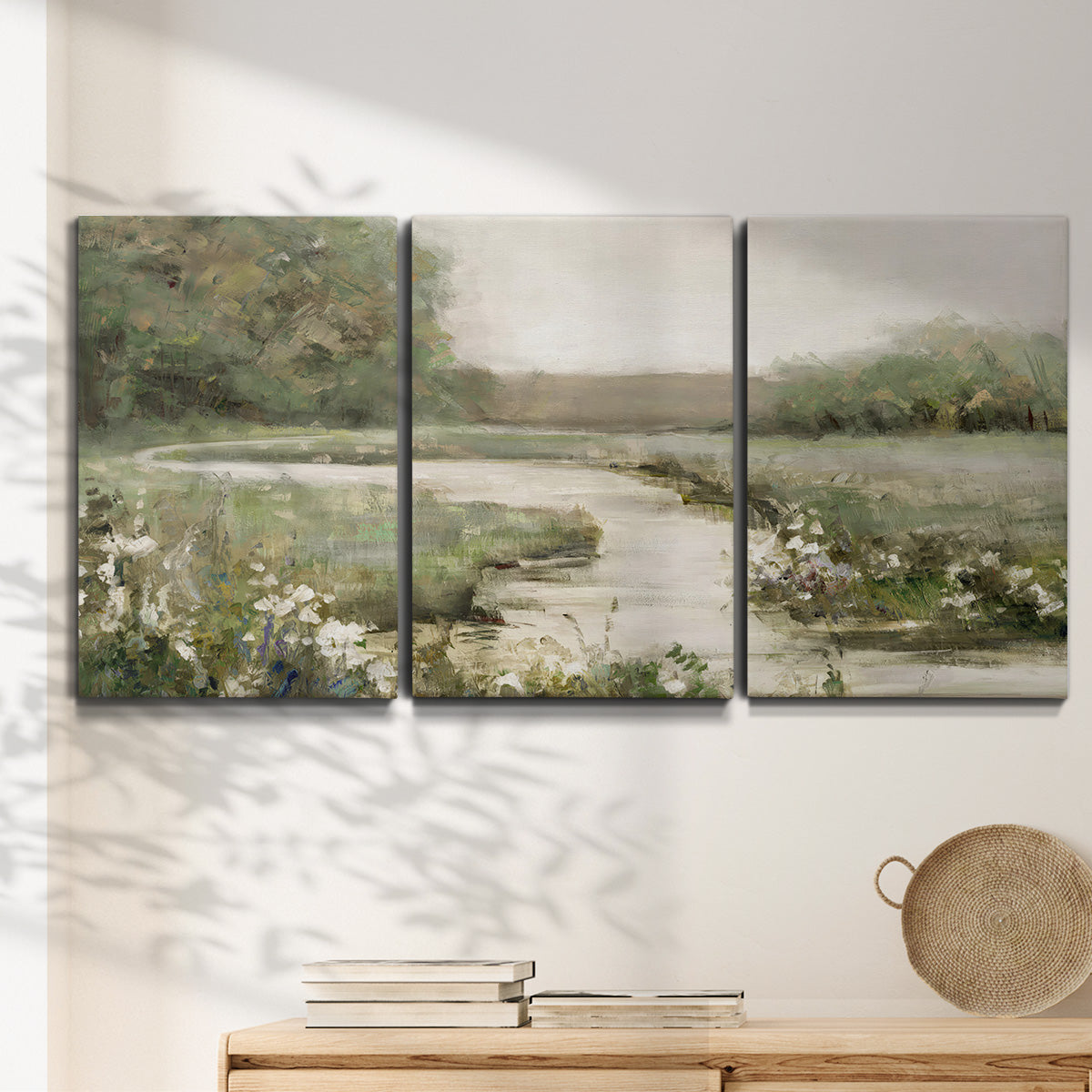 Three-panel canvas wall art featuring narrow path through quiet landscape, displayed in a minimalist living room above a console table.