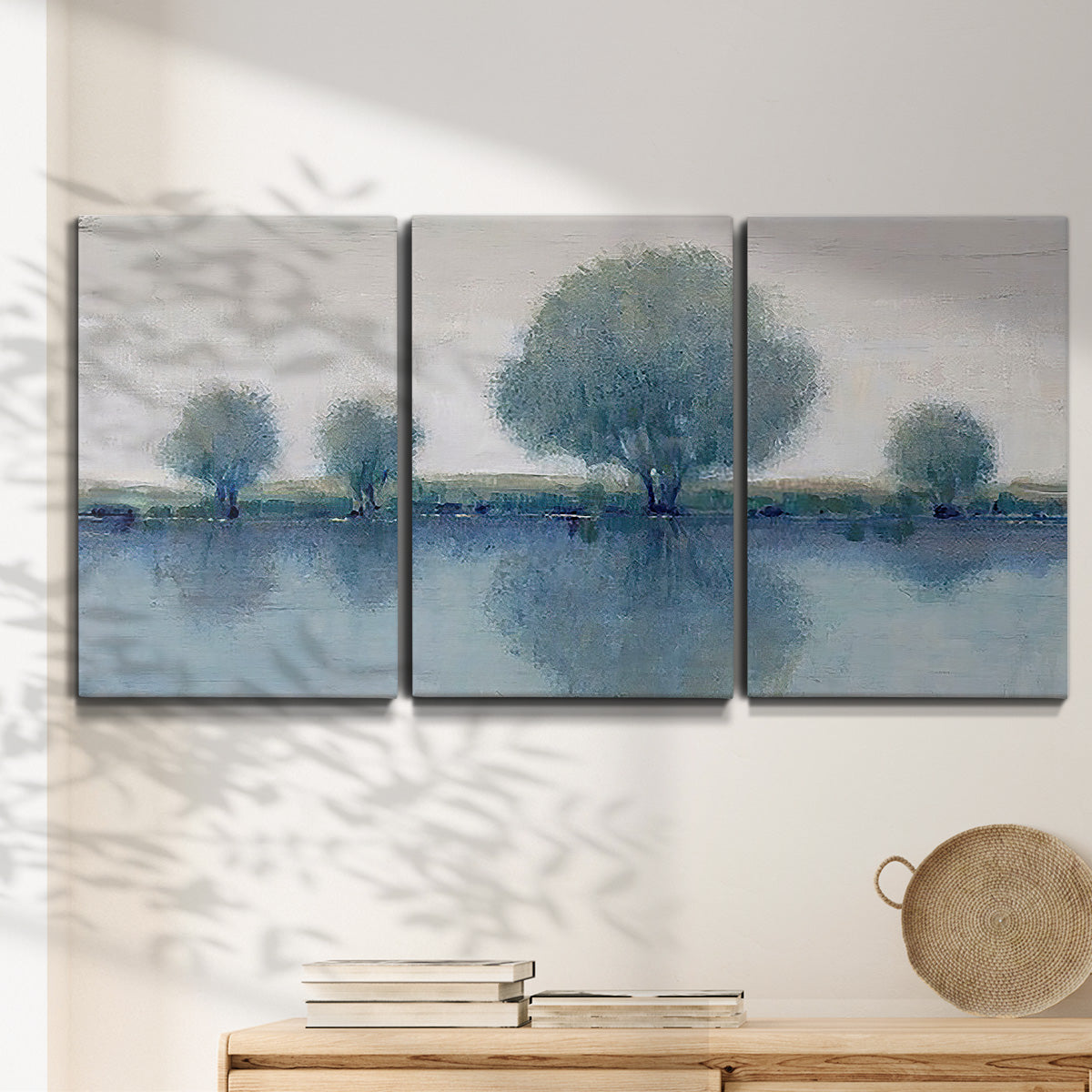Three-panel canvas wall art featuring calm afternoon river reflection, displayed in a minimalist living room above a console table.