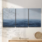 Three-panel canvas wall art featuring grayscale seascape with horizon, displayed in a minimalist living room above a console table.