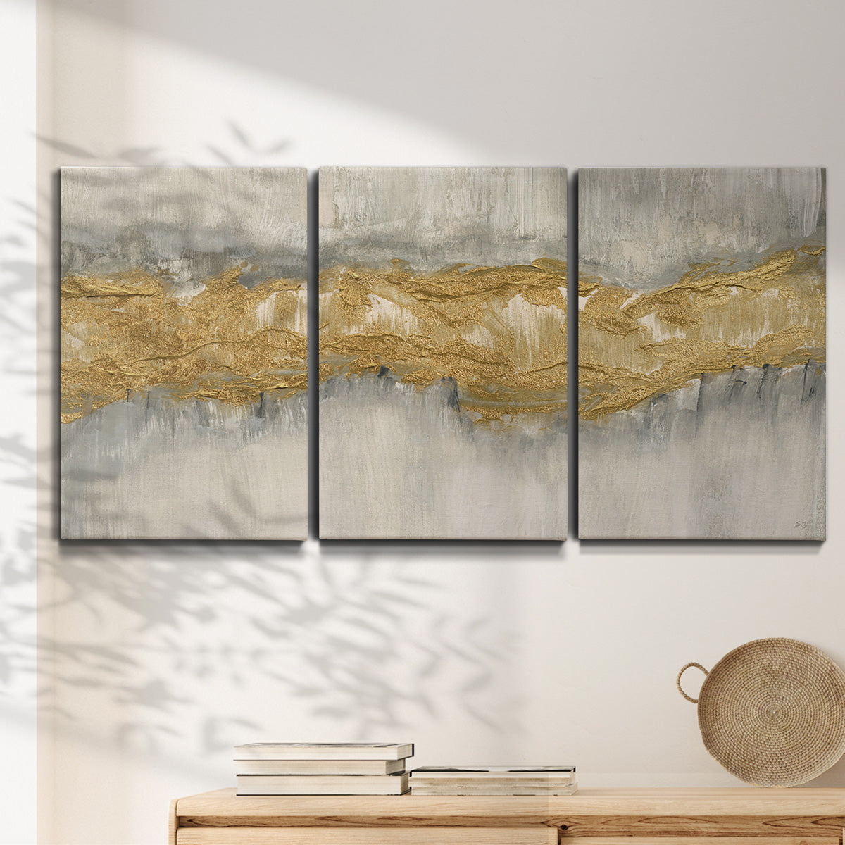 Three-panel canvas wall art featuring flowing abstract golden tones, displayed in a minimalist living room above a console table.