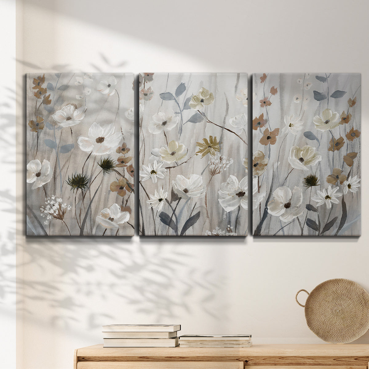 Three-panel canvas wall art featuring misty wildflower meadow landscape, displayed in a minimalist living room above a console table.