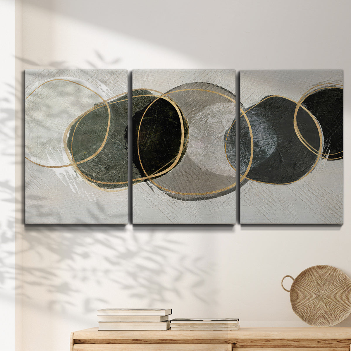 Three-panel canvas wall art featuring smooth abstract river stone forms, displayed in a minimalist living room above a console table.
