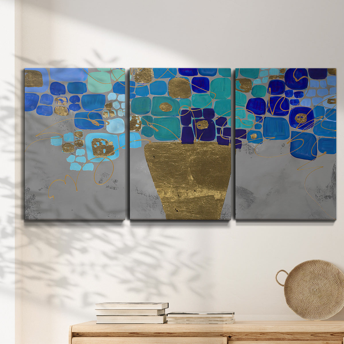 Three-panel canvas wall art featuring blue floral abstract botanical expression, displayed in a minimalist living room above a console table.