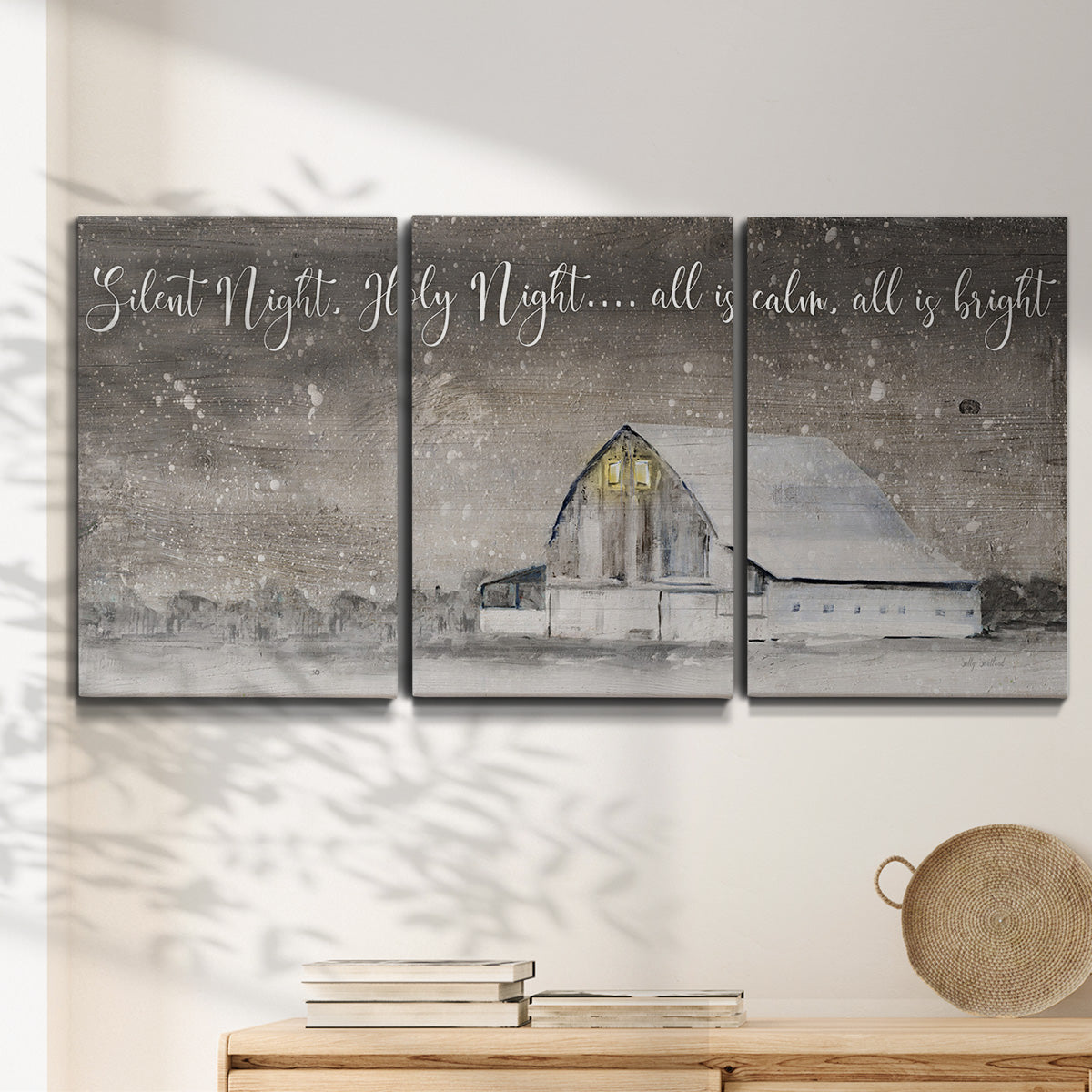 Three-panel canvas wall art featuring rustic winter holiday text art, displayed in a minimalist living room above a console table.