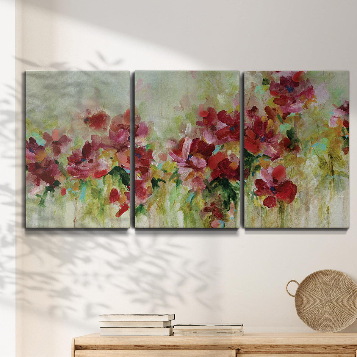 Three-panel canvas wall art featuring colorful floral garden composition, displayed in a minimalist living room above a console table.