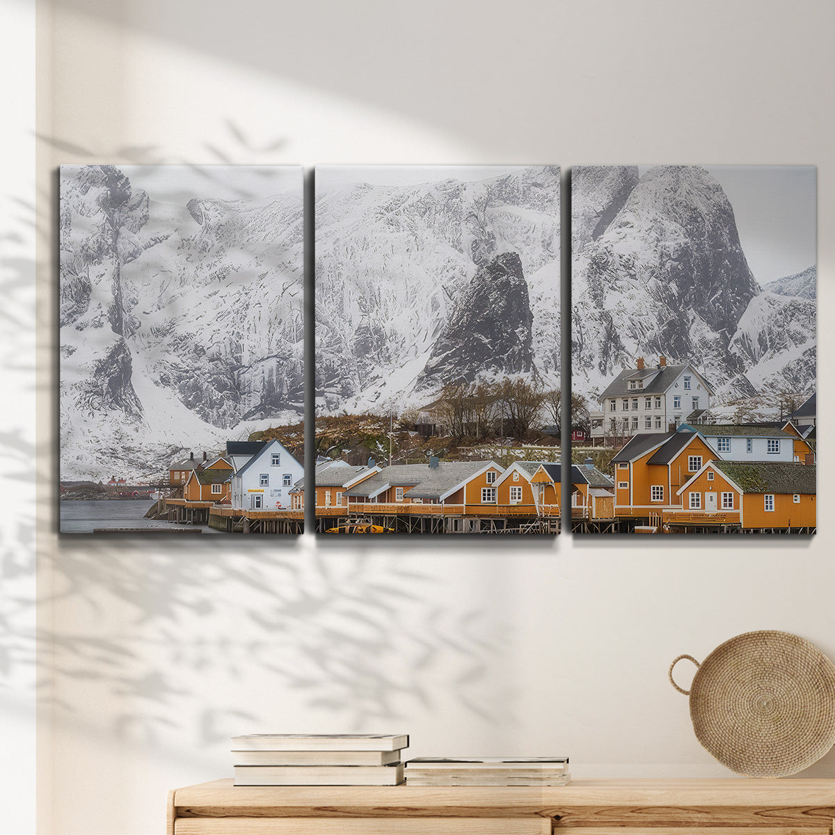 Three-panel canvas wall art featuring winter village street photography, displayed in a minimalist living room above a console table.