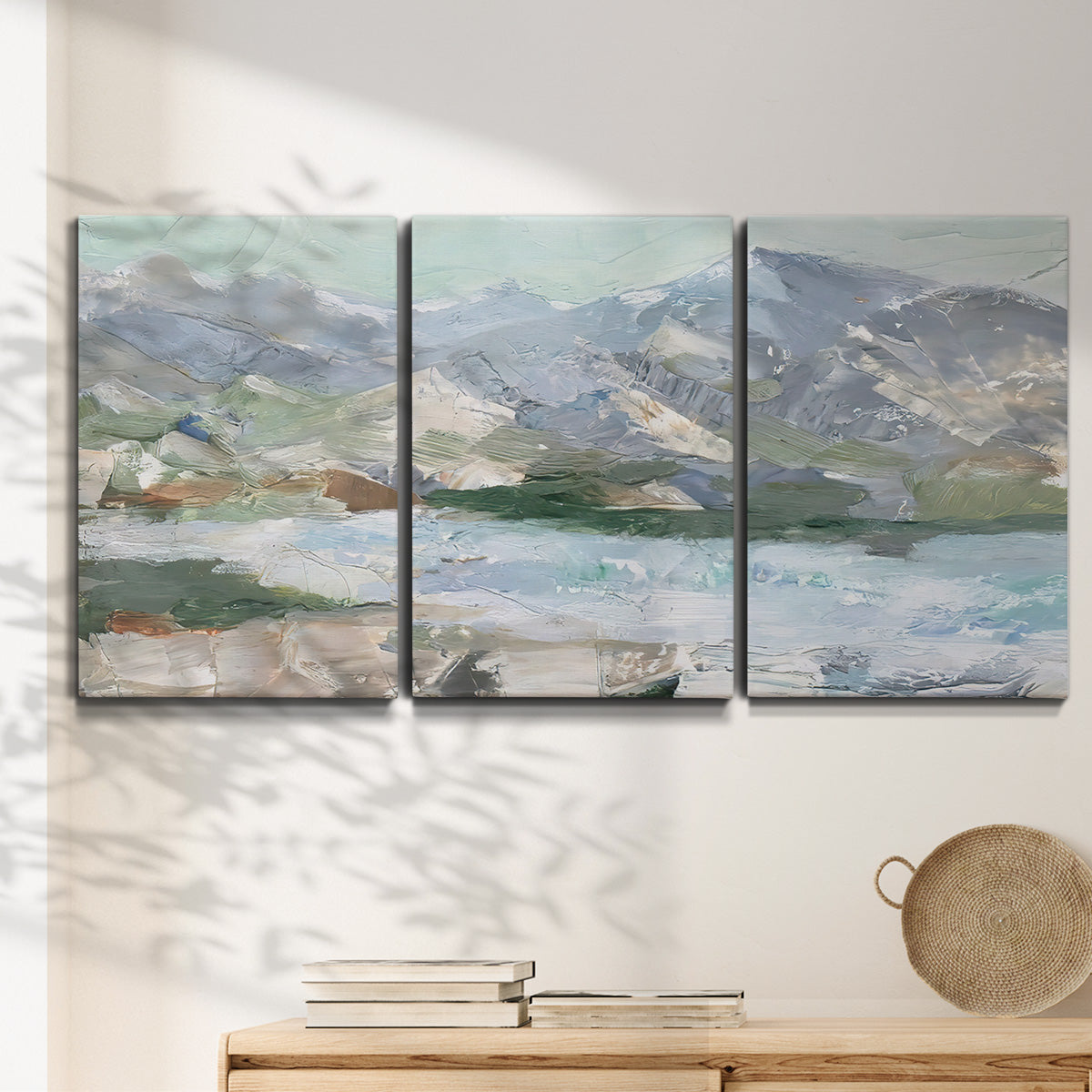 Three-panel canvas wall art featuring pastel mountain landscape view, displayed in a minimalist living room above a console table.