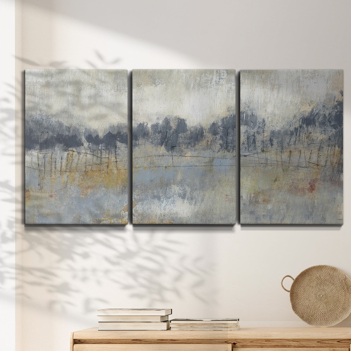 Three-panel canvas wall art featuring soft grey abstract horizon, displayed in a minimalist living room above a console table.